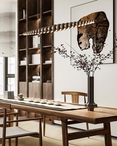 a dining room table with plates and cups on it in front of a bookcase