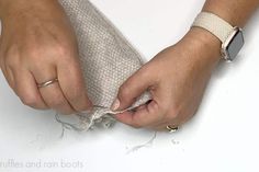 a person is sewing something on a piece of white fabric with two hands holding it