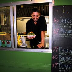 a man standing in front of a window holding a sandwich