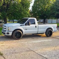 a white pickup truck parked on the side of a road in front of some trees