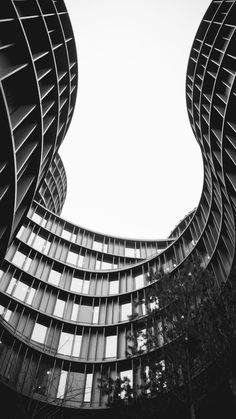 two tall buildings that are next to each other in black and white, with the sky behind them