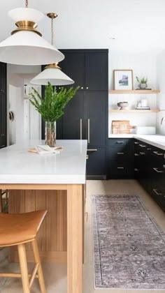 a kitchen with black cabinets, white counter tops and an area rug on the floor