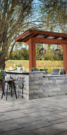 an outdoor kitchen with stone walls and grilling area