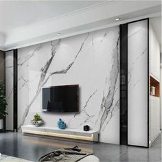 a living room with white marble walls and black accents on the tv stand is shown