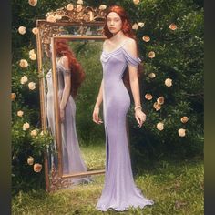 a woman standing in front of a mirror wearing a purple dress and holding her hand on her hip