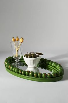 a green tray with olives and other items on it, along with a glass vase