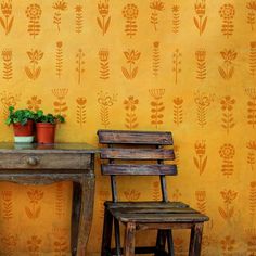 two wooden chairs sitting next to a table with a potted plant on it