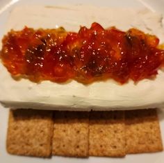 a plate with crackers, cheese and sauce on it