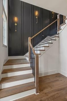 an empty room with black walls and wooden floors, two lights are on the wall next to the stairs