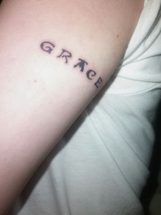 a person with a tattoo on their arm that says grace in black ink and the word grace is written across it