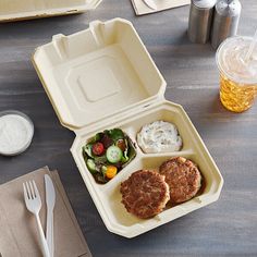 an open takeout box with food on the table next to utensils and drinks