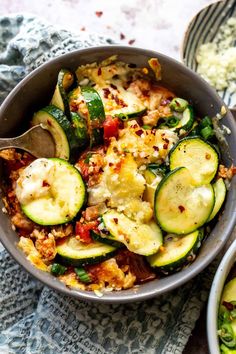 a bowl filled with zucchini and other food on top of a blue towel