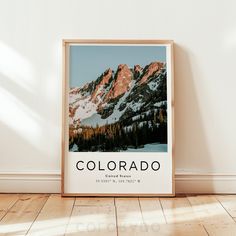 a framed poster with the word colorado on it in front of a white wall and wooden floor