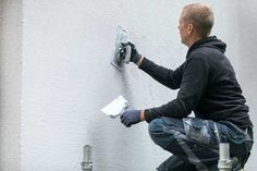 a man in black jacket and gloves working on a wall