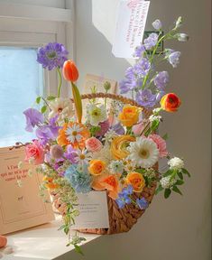 a basket filled with lots of flowers sitting on top of a window sill next to a card