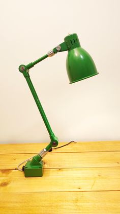 a green desk lamp sitting on top of a wooden table