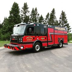 a red and black fire truck parked in front of some trees