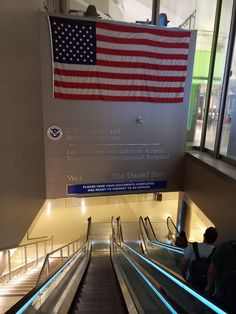 an american flag hanging on the wall above escalators