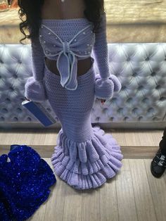 a woman in a purple dress standing next to a white couch with blue sequins on it