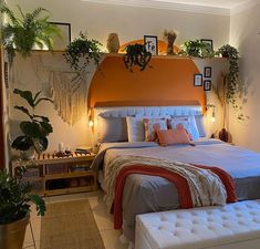 a large bed sitting in a bedroom next to a wall mounted planter and potted plants