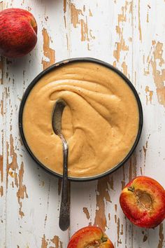 an apple and cinnamon dip in a bowl with apples around it on a white wooden table