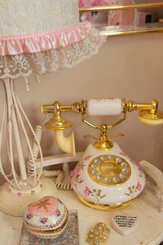 an old fashioned phone sitting on top of a white table next to a pink lamp