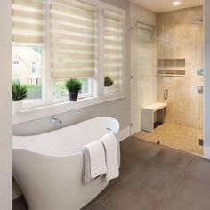 a bathroom with a tub, toilet and shower in it's center wall next to a walk - in shower