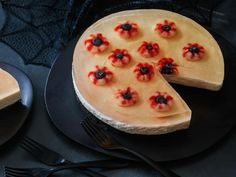 a cheesecake decorated with red flowers on a black plate