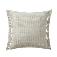 a white pillow with tassels on the front and back of it, against a white background