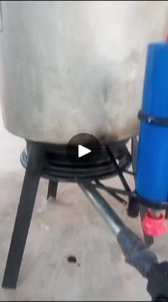 a large metal tank sitting on top of a table next to a blue barrel and hose