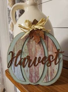 a wooden sign sitting on top of a table next to a white pitcher and vase