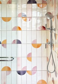 a shower head and hand rail in a bathroom with colorful tiles on the wall behind it