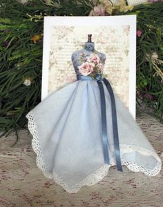 a card with a blue dress and flowers on it