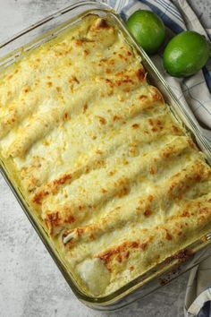 a casserole dish with cheese and some limes on the table next to it