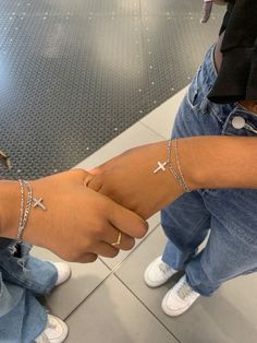 two people wearing cross bracelets on their arm with one holding the other's hand