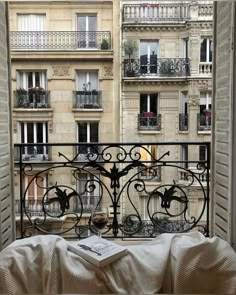 an open window with a view of the city from it's balcony, looking out at buildings