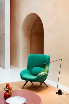 a green chair sitting on top of a wooden floor next to a table with a tomato