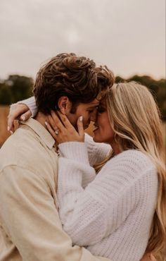 a man and woman embracing each other in an open field