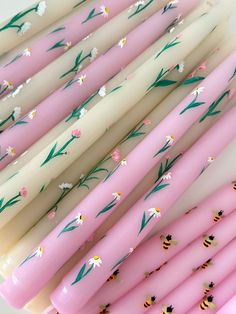 several pink and white candles with flowers on them are lined up next to each other