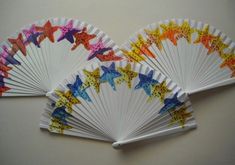 four paper fans with different designs on them, one is folded and the other has stars