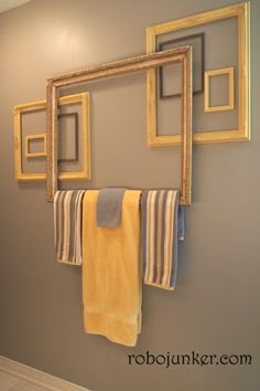 a towel rack is hanging on the wall in front of a mirror and two framed pictures