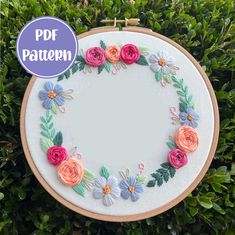 an embroidery pattern with flowers and leaves on it, in the middle of some bushes