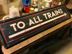 an old to all trains sign sitting on top of a wooden table in a garage