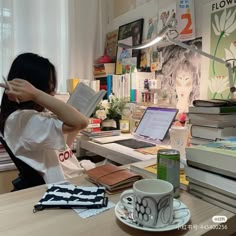 a woman sitting at a desk reading a book and holding her head in her hands