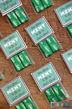 some green and white candy sticks are sitting on a wooden table with tags attached to them