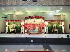 the stage is decorated with red and white flowers, greenery, and gold accents