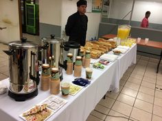 a man standing in front of a table filled with food and drinks on top of it