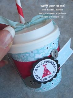 a hand holding a cup with a straw in it and a tag on the lid