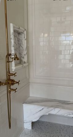 a bathroom with white marble and gold fixtures