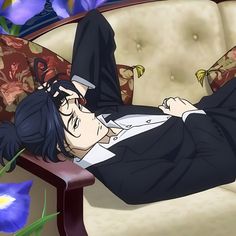 a man laying on top of a couch next to purple flowers